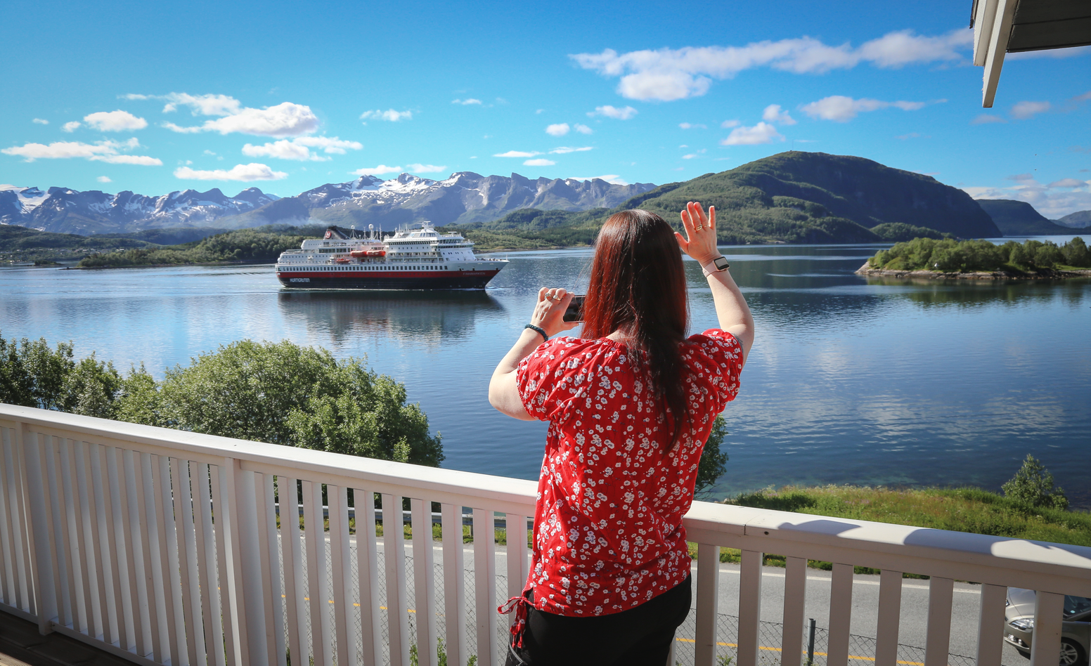 Eva Rendal står i huset og vinker til Hurtigruten, som seiler forbi