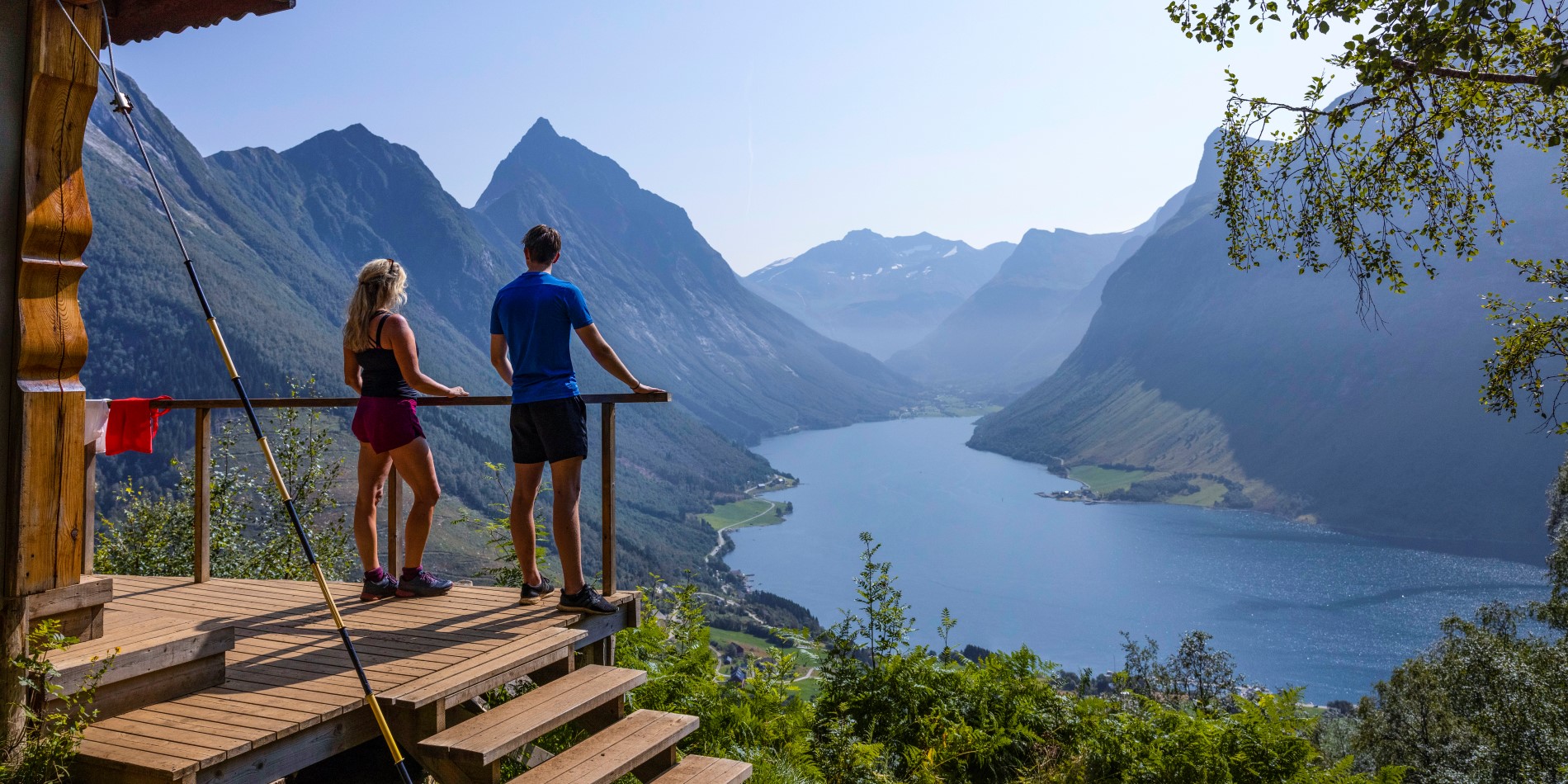 Et par som står på et utsiktspunkt over Hjørundfjorden Vestkysten i Norge