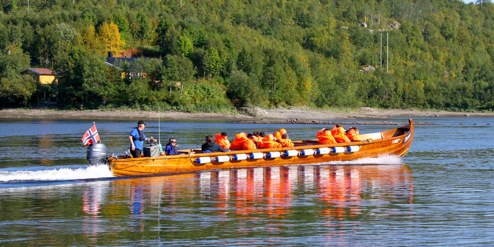 En gruppe mennesker rir på baksiden av en båt i vannet
