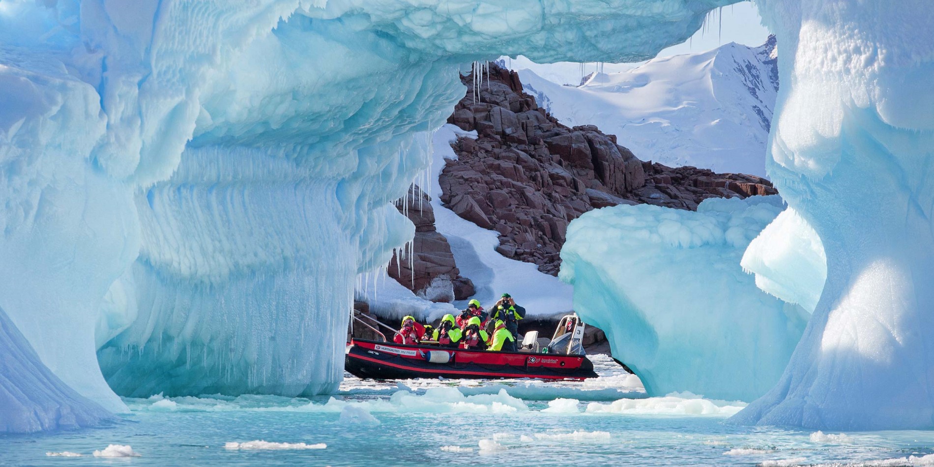 Gruppe av turister i liten båt blant spektakulære is formasjoner